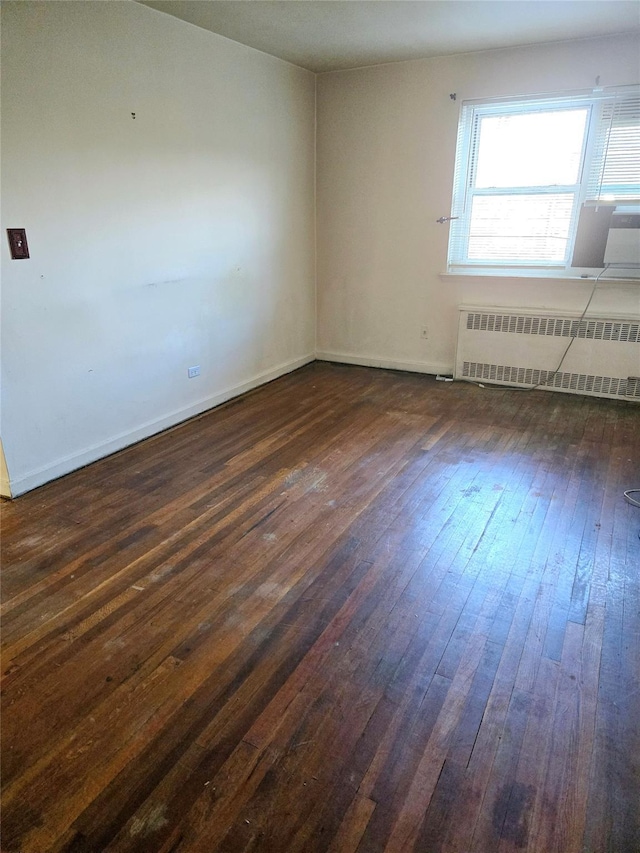 spare room with dark hardwood / wood-style floors and radiator heating unit