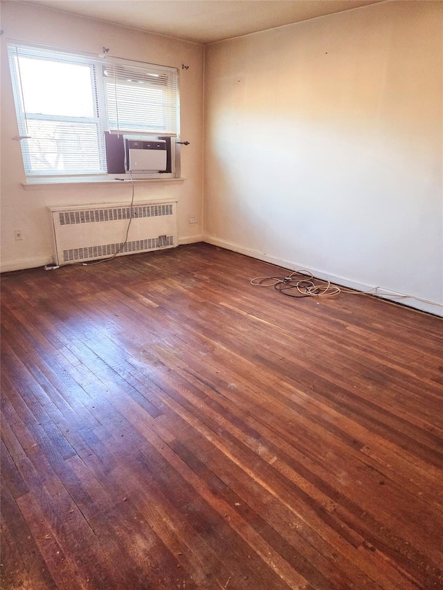 unfurnished room featuring radiator heating unit and dark hardwood / wood-style floors