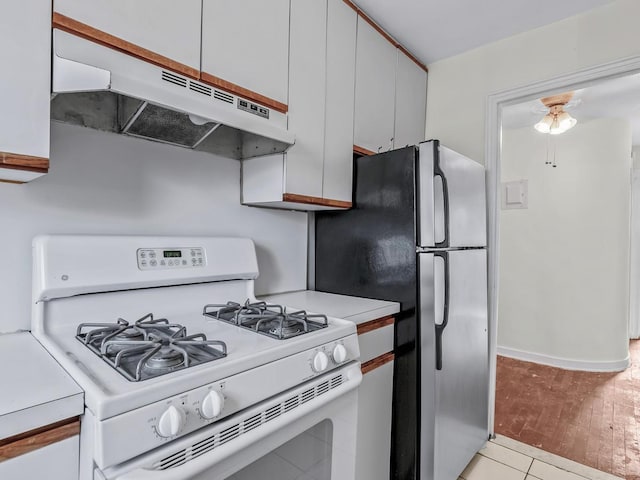 kitchen featuring white range with gas cooktop, white cabinetry, and stainless steel refrigerator