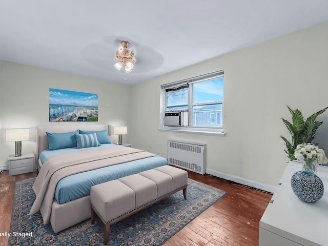 bedroom featuring dark hardwood / wood-style floors, cooling unit, radiator heating unit, and ceiling fan