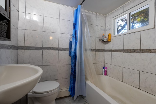 full bathroom with shower / bath combo with shower curtain, sink, tile walls, tile patterned flooring, and toilet