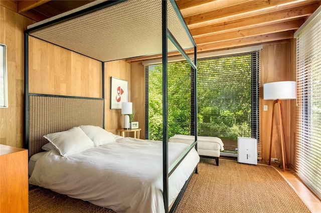 unfurnished bedroom with beamed ceiling and wooden walls