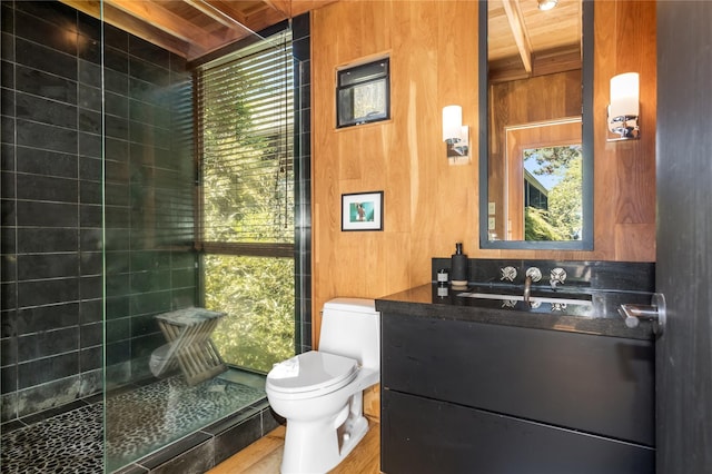 bathroom with beamed ceiling, toilet, wooden walls, vanity, and wood ceiling