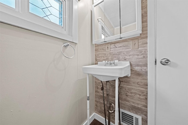 bathroom with wooden walls, visible vents, and crown molding