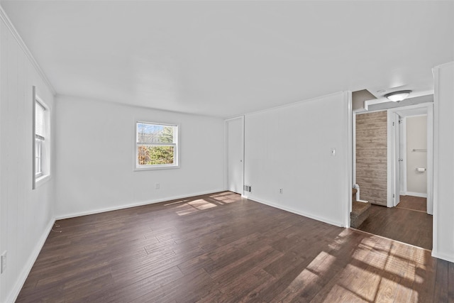 empty room featuring ornamental molding, wooden walls, and dark wood-type flooring