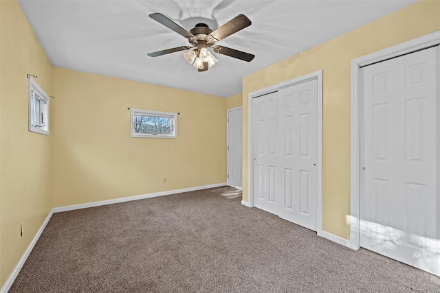 unfurnished bedroom with carpet flooring, ceiling fan, and multiple closets