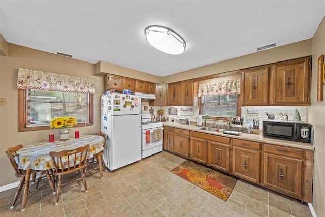 kitchen featuring white appliances, tasteful backsplash, plenty of natural light, and sink