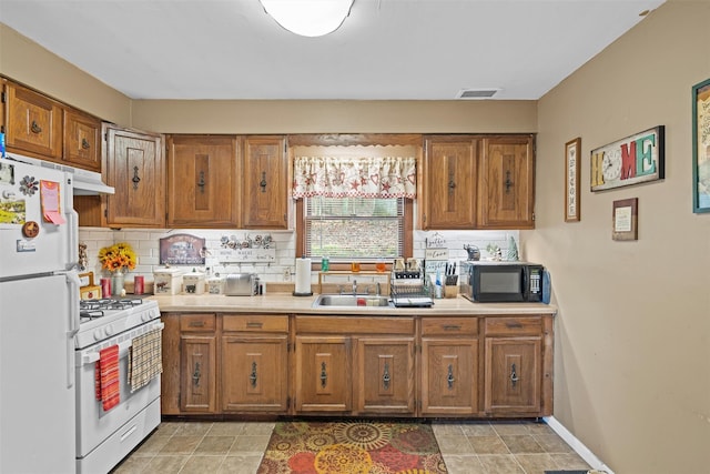 kitchen featuring white appliances, backsplash, and sink