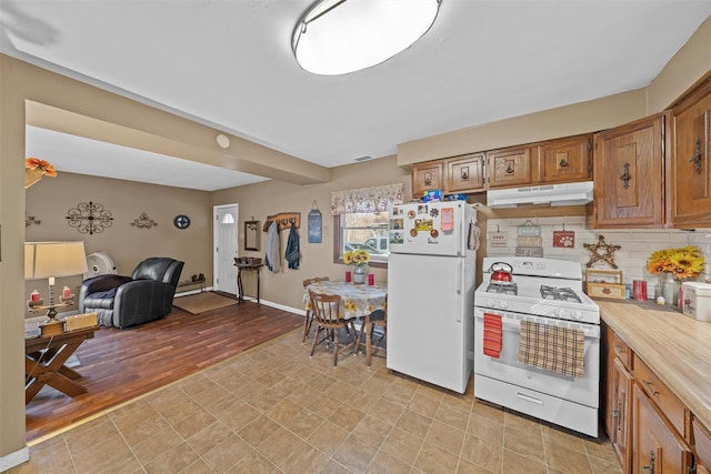 kitchen with backsplash, light hardwood / wood-style floors, and white appliances