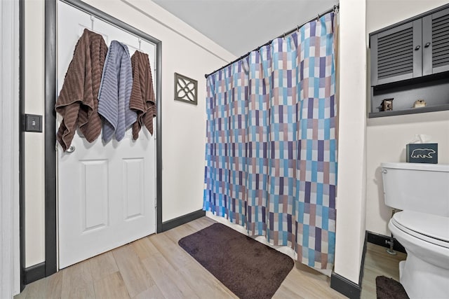 bathroom with curtained shower, toilet, and wood-type flooring