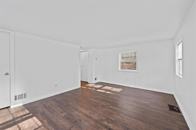 empty room with crown molding, visible vents, and wood finished floors