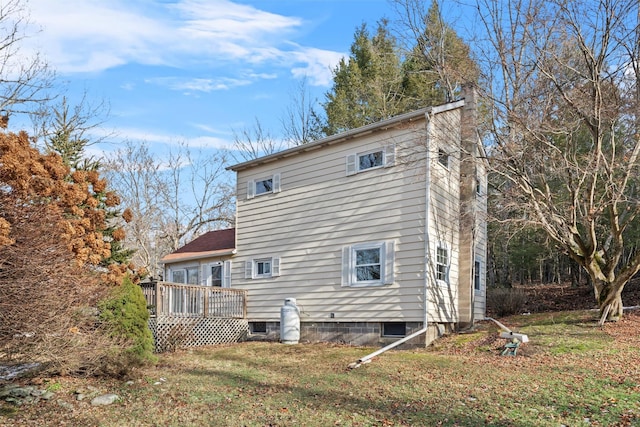 rear view of property featuring a chimney, a deck, and a lawn