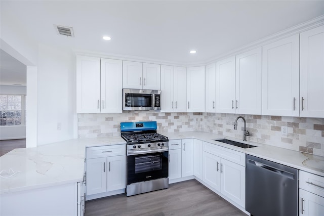 kitchen featuring decorative backsplash, white cabinetry, sink, and appliances with stainless steel finishes