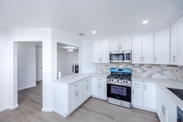 kitchen featuring light wood-type flooring, white cabinetry, backsplash, and appliances with stainless steel finishes