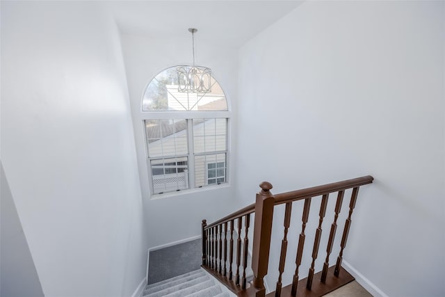 stairs with a notable chandelier