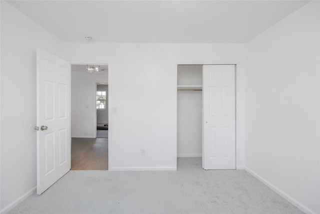 unfurnished bedroom with light colored carpet and a closet