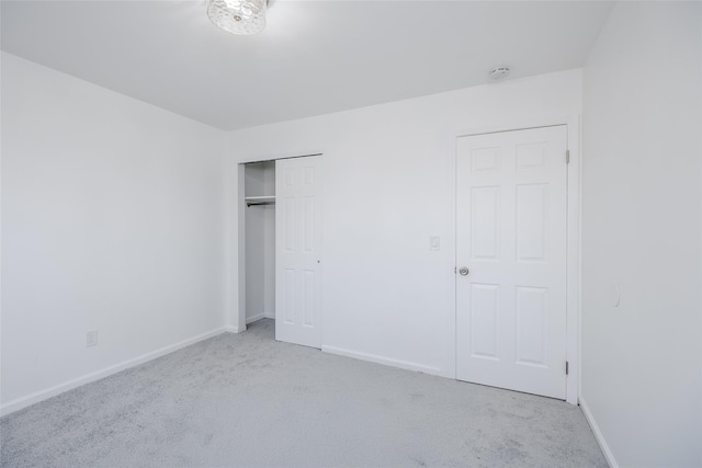 unfurnished bedroom with light colored carpet and a closet