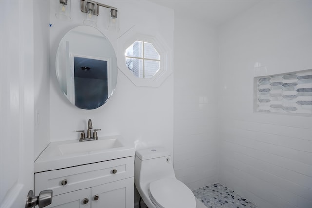 bathroom featuring tiled shower, vanity, and toilet