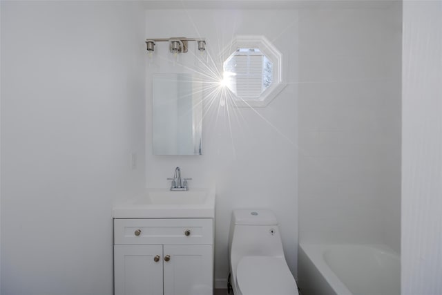 bathroom with a tub to relax in, vanity, and toilet