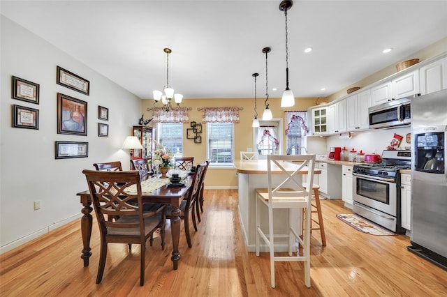 kitchen featuring stainless steel appliances, decorative light fixtures, an inviting chandelier, light hardwood / wood-style flooring, and white cabinets