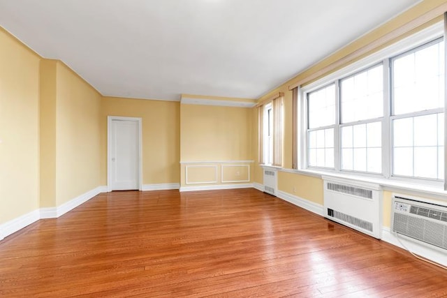 empty room featuring baseboards, radiator heating unit, and light wood-style floors