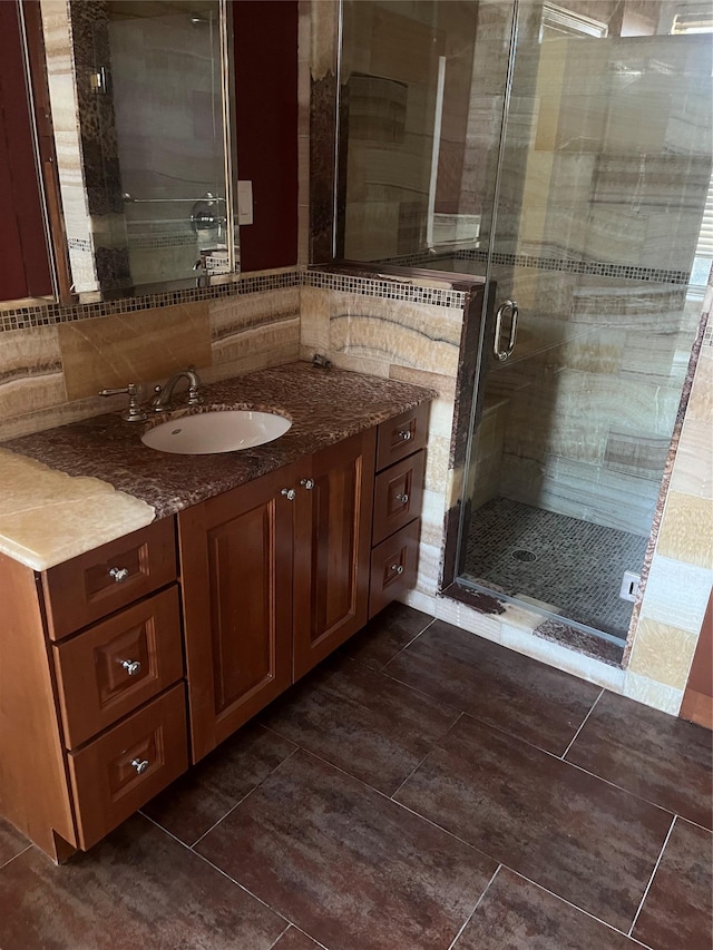 bathroom featuring tile patterned floors, backsplash, vanity, and a shower stall