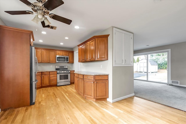 kitchen featuring ceiling fan, light hardwood / wood-style floors, light stone counters, and appliances with stainless steel finishes