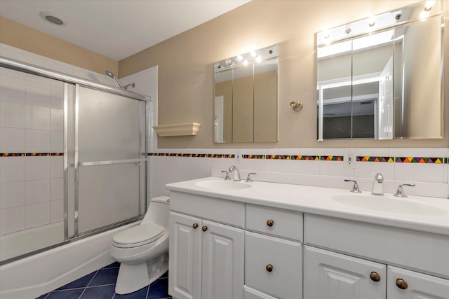 full bathroom featuring vanity, shower / bath combination with glass door, tile patterned floors, toilet, and tasteful backsplash