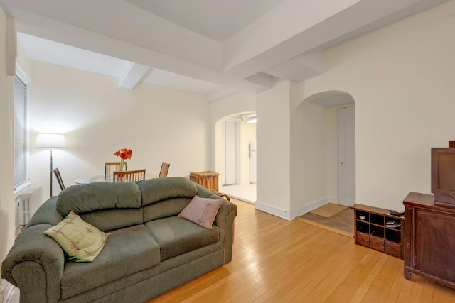 living room featuring beamed ceiling and light hardwood / wood-style floors