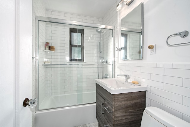 full bathroom with vanity, toilet, tile walls, and enclosed tub / shower combo