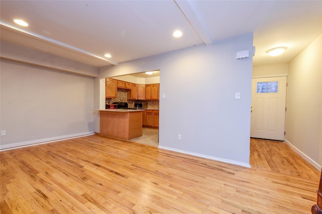 kitchen featuring kitchen peninsula, light hardwood / wood-style floors, black range, and tasteful backsplash