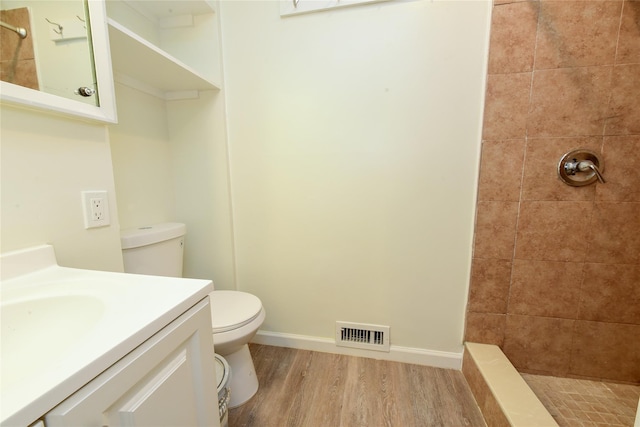 bathroom featuring tiled shower, wood-type flooring, vanity, and toilet