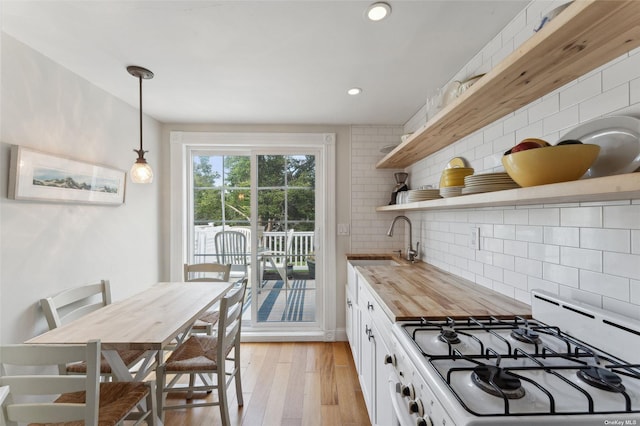 kitchen featuring a sink, backsplash, butcher block countertops, white gas range, and open shelves