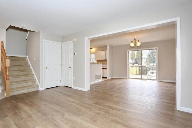 unfurnished living room featuring a chandelier and light hardwood / wood-style floors