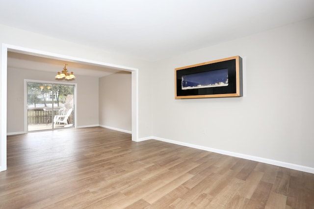 unfurnished room with hardwood / wood-style flooring and a notable chandelier