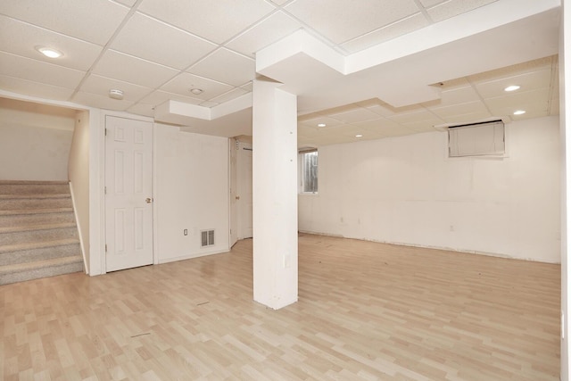 basement with a paneled ceiling and light wood-type flooring