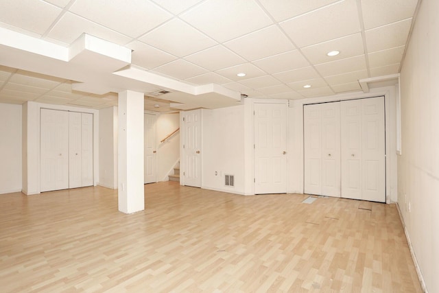 basement with a drop ceiling and light wood-type flooring