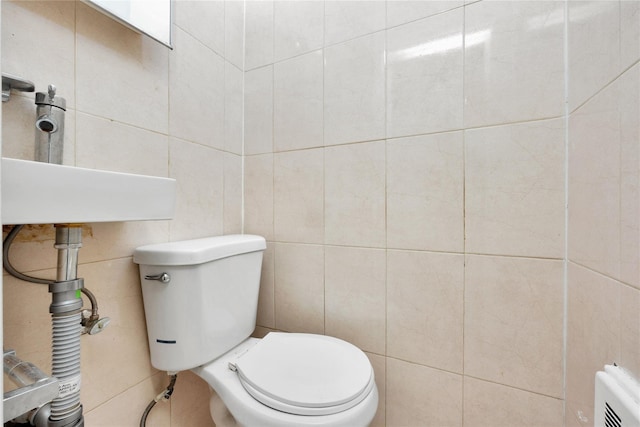 bathroom with radiator heating unit, tile walls, and toilet