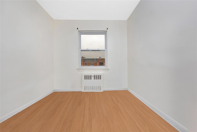 spare room featuring wood-type flooring and radiator