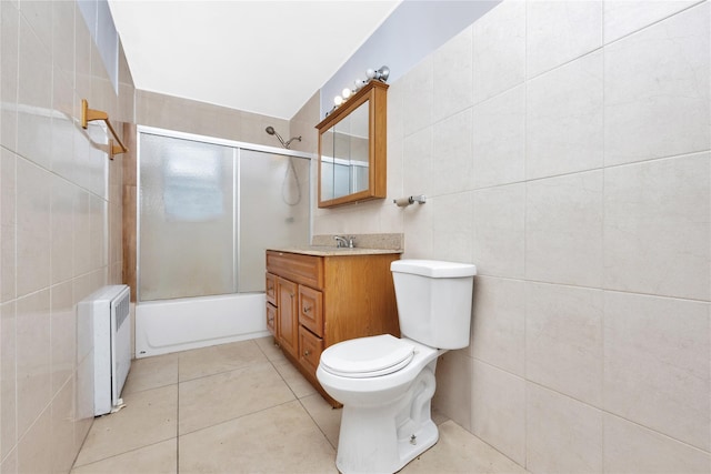 full bathroom with vanity, shower / bath combination with glass door, tile patterned floors, toilet, and tile walls