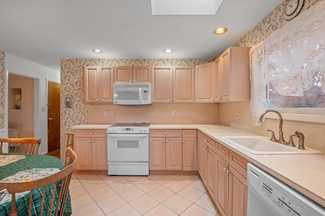 kitchen with light brown cabinets, white appliances, sink, a skylight, and light tile patterned floors