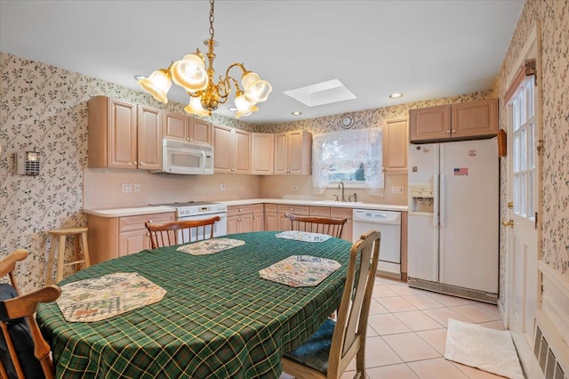 kitchen with a skylight, sink, pendant lighting, white appliances, and light brown cabinetry