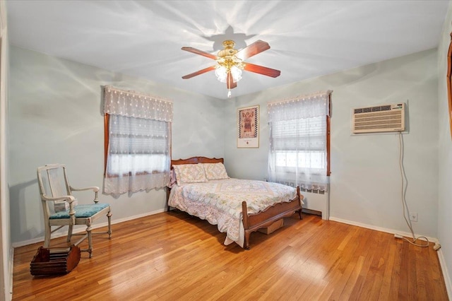 bedroom with a wall unit AC, ceiling fan, and light hardwood / wood-style floors