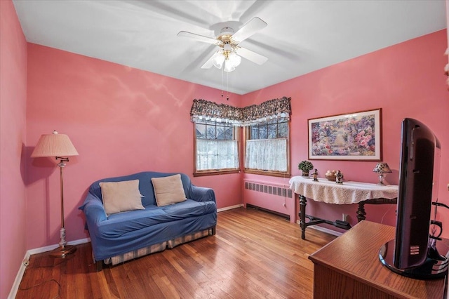 living area featuring hardwood / wood-style flooring, ceiling fan, and radiator