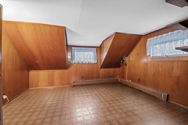 bonus room featuring a baseboard heating unit, vaulted ceiling, a healthy amount of sunlight, and wood walls