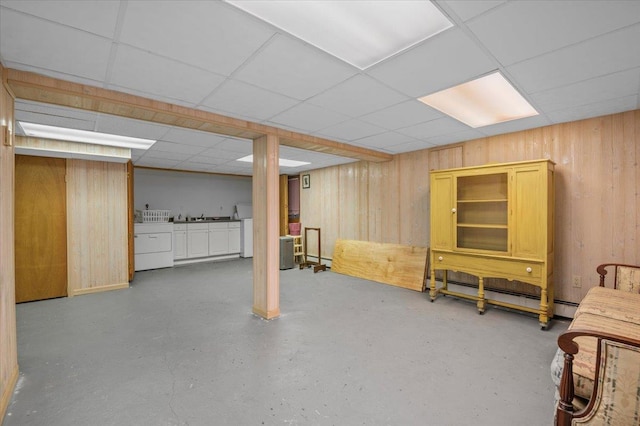 basement with a paneled ceiling, wooden walls, and washer and clothes dryer