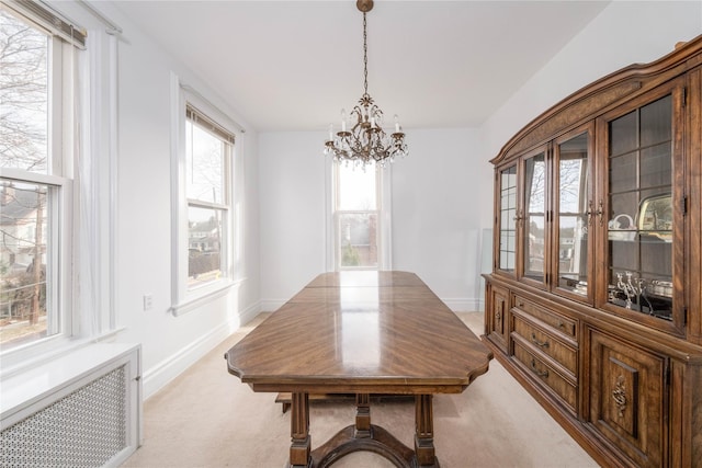 dining room featuring radiator heating unit, light colored carpet, and a notable chandelier