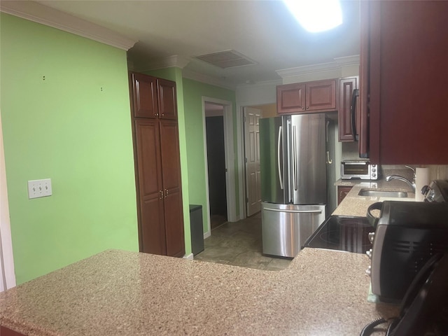 kitchen with a sink, visible vents, light countertops, ornamental molding, and freestanding refrigerator