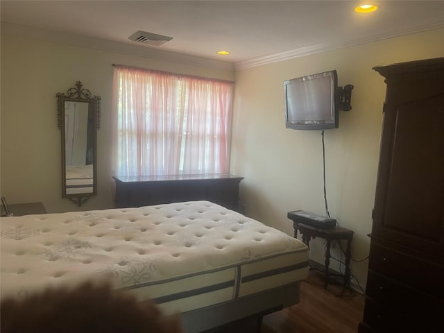 bedroom featuring crown molding, visible vents, and wood finished floors