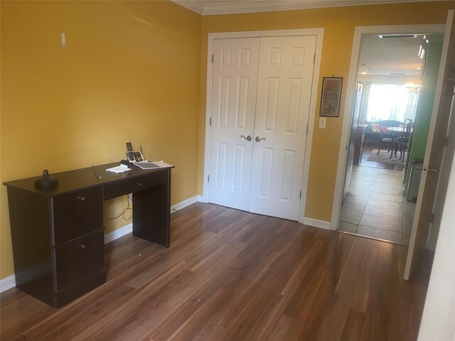 unfurnished office with dark wood-type flooring, crown molding, and baseboards